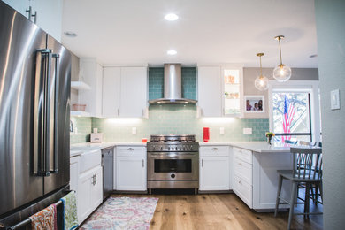 This is an example of a large transitional l-shaped eat-in kitchen in Austin with a farmhouse sink, shaker cabinets, white cabinets, quartzite benchtops, blue splashback, subway tile splashback, stainless steel appliances, medium hardwood floors and a peninsula.