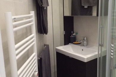 パリにある低価格の中くらいなコンテンポラリースタイルのおしゃれなバスルーム (浴槽なし) (バリアフリー、白い壁、セメントタイルの床、壁付け型シンク、グレーの床、引戸のシャワー、フラットパネル扉のキャビネット、黒いキャビネット、分離型トイレ、ベージュのタイル、グレーのタイル、セラミックタイル、白い洗面カウンター) の写真