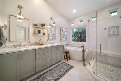 Inspiration for a medium sized beach style ensuite bathroom in Orange County with shaker cabinets, green cabinets, a freestanding bath, a corner shower, white tiles, porcelain tiles, beige walls, marble flooring, a submerged sink, engineered stone worktops, white floors, a hinged door, white worktops, a shower bench, double sinks, a built in vanity unit and a vaulted ceiling.