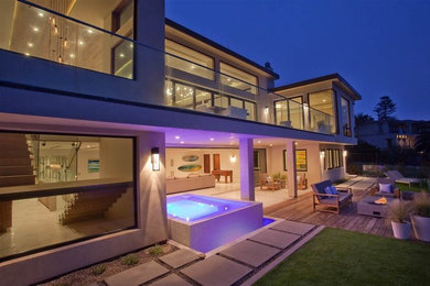 Inspiration for a large contemporary backyard stone patio remodel in San Diego with a roof extension