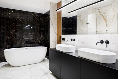 Design ideas for a large contemporary bathroom in London with flat-panel cabinets, black cabinets, a freestanding bath, a wall mounted toilet, black and white tiles, marble tiles, multi-coloured walls, marble flooring, a wall-mounted sink, white floors, a hinged door, double sinks, a floating vanity unit and wood walls.