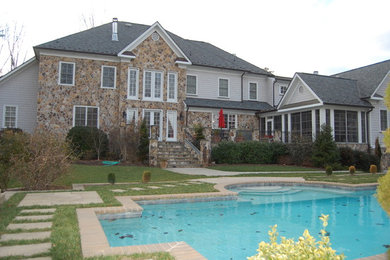 This is an example of a large traditional two-storey beige house exterior in Richmond with stone veneer, a hip roof and a shingle roof.