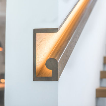 Freistehende Kragarmtreppe mit beleuchtetem Handlauf