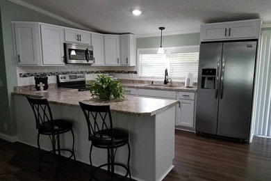 Open concept kitchen - small transitional u-shaped brown floor open concept kitchen idea in Chicago with white cabinets, stainless steel appliances and a peninsula