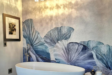 Mid-sized trendy ceramic tile and wallpaper freestanding bathtub photo in London with a wall-mount toilet and white walls