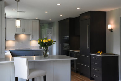 Example of a mid-sized country u-shaped medium tone wood floor eat-in kitchen design in Toronto with a double-bowl sink, shaker cabinets, gray cabinets, quartz countertops, gray backsplash, paneled appliances, a peninsula and gray countertops