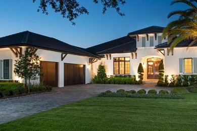 This is an example of a large arts and crafts one-storey stucco white house exterior in Orlando with a hip roof and a shingle roof.