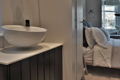 Bathroom - small coastal master travertine floor and multicolored floor bathroom idea in Devon with beaded inset cabinets, black cabinets, solid surface countertops and white countertops