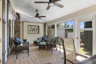 Elegant stone screened-in back porch photo in Other with a roof extension