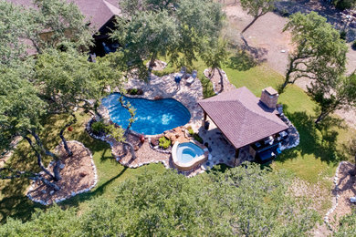 Pool house - large traditional backyard custom-shaped pool house idea in Austin with decking