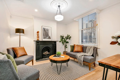 Inspiration for a transitional living room in Melbourne with white walls, light hardwood floors and a standard fireplace.