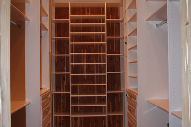 Example of a large minimalist gender-neutral dark wood floor walk-in closet design in Miami with open cabinets and white cabinets