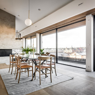 Idéer för en nordisk matplats med öppen planlösning, med vita väggar, ljust trägolv, en dubbelsidig öppen spis, en spiselkrans i betong och grått golv