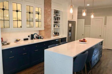 Small transitional l-shaped medium tone wood floor and brown floor eat-in kitchen photo in Dallas with a farmhouse sink, shaker cabinets, blue cabinets, quartzite countertops, white backsplash, subway tile backsplash, stainless steel appliances, an island and white countertops