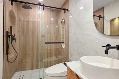 Example of a small beige tile and porcelain tile porcelain tile, beige floor and single-sink sliding shower door design in DC Metro with furniture-like cabinets, light wood cabinets, a one-piece toilet, white walls, quartz countertops, white countertops, a niche and a floating vanity