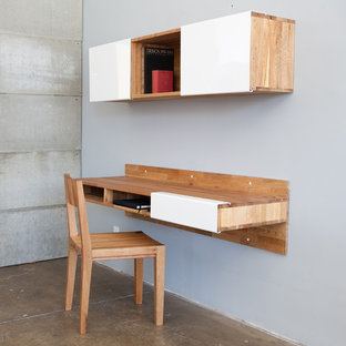 This is an example of a small modern study in Los Angeles with grey walls, concrete flooring and a built-in desk.
