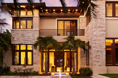 Large contemporary beige two-story stone exterior home idea in Miami with a hip roof