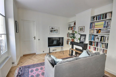 Inspiration pour un salon traditionnel de taille moyenne avec une bibliothèque ou un coin lecture, un mur beige, un sol en bois brun, une cheminée standard et un téléviseur indépendant.