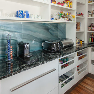 Contemporary kitchen pantry in Gold Coast - Tweed with an undermount sink, flat-panel cabinets, white cabinets, marble benchtops, blue splashback, glass sheet splashback, stainless steel appliances, medium hardwood floors and with island.