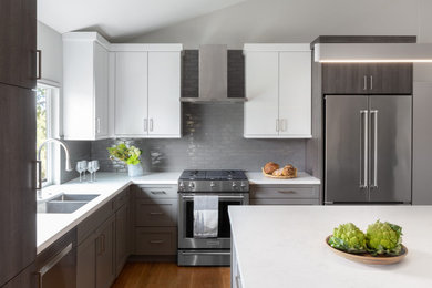 Mid-sized contemporary u-shaped kitchen in San Francisco with a double-bowl sink, flat-panel cabinets, grey splashback, ceramic splashback, stainless steel appliances, light hardwood floors and with island.