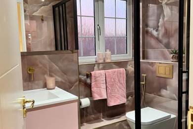 This is an example of a small modern bathroom in London with a corner shower, pink tiles, ceramic tiles, ceramic flooring, green floors, a hinged door, a single sink and a floating vanity unit.