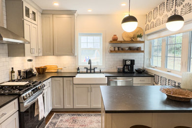 Inspiration for a mid-sized eclectic dark wood floor and brown floor enclosed kitchen remodel in Wilmington with a farmhouse sink, shaker cabinets, beige cabinets, solid surface countertops, white backsplash, ceramic backsplash, stainless steel appliances, an island and black countertops