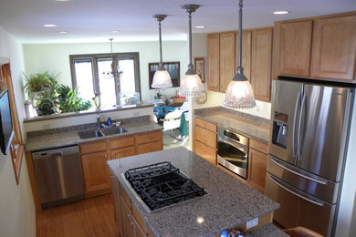 Mid-sized u-shaped light wood floor and brown floor eat-in kitchen photo with a double-bowl sink, light wood cabinets, granite countertops, stainless steel appliances and an island