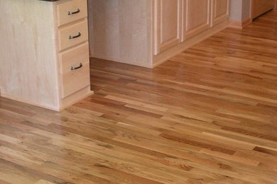 Example of a large classic l-shaped light wood floor and brown floor eat-in kitchen design in Minneapolis with light wood cabinets, granite countertops, a drop-in sink, raised-panel cabinets, stainless steel appliances and an island