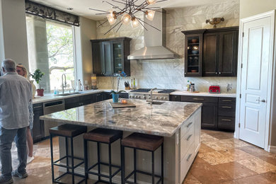 Inspiration for a mid-sized transitional l-shaped travertine floor and beige floor open concept kitchen remodel in Phoenix with an undermount sink, shaker cabinets, dark wood cabinets, onyx countertops, gray backsplash, marble backsplash, stainless steel appliances, an island and multicolored countertops