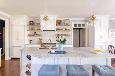 Example of a classic galley medium tone wood floor and brown floor kitchen design in Raleigh with an undermount sink, shaker cabinets, white cabinets, gray backsplash, subway tile backsplash, stainless steel appliances, an island and gray countertops