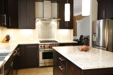 Inspiration for a large transitional u-shaped limestone floor enclosed kitchen remodel in San Diego with a farmhouse sink, shaker cabinets, dark wood cabinets, granite countertops, white backsplash, subway tile backsplash, stainless steel appliances and an island