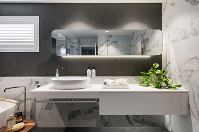 Design ideas for a contemporary bathroom in Brisbane with flat-panel cabinets, white cabinets, a freestanding tub, gray tile, white tile, grey walls, a vessel sink, grey floor and white benchtops.