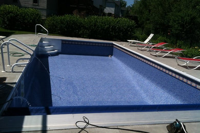 Foto de piscina alargada tradicional de tamaño medio rectangular en patio trasero con losas de hormigón