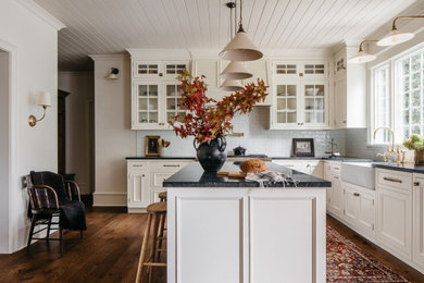 Elegant shiplap ceiling kitchen photo in Chicago with a farmhouse sink, white cabinets, white backsplash, an island and glass-front cabinets