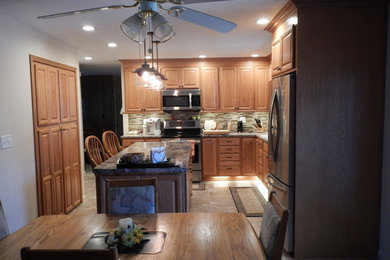 Eat-in kitchen - traditional l-shaped ceramic tile eat-in kitchen idea in Chicago with an undermount sink, raised-panel cabinets, medium tone wood cabinets, laminate countertops, multicolored backsplash, mosaic tile backsplash, stainless steel appliances and an island