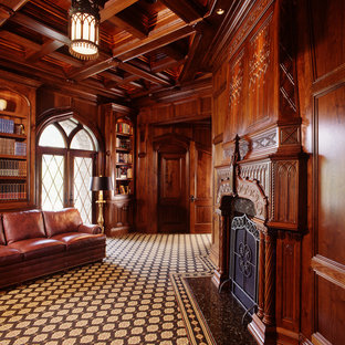 Exempel på ett mycket stort medelhavsstil hemmabibliotek, med bruna väggar, heltäckningsmatta, en standard öppen spis, ett fristående skrivbord och en spiselkrans i sten