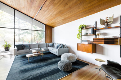 Example of a large 1950s open concept light wood floor and beige floor living room design in Portland with white walls, a standard fireplace, a stone fireplace and no tv