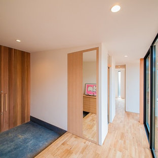 他の地域の中サイズの両開きドアコンテンポラリースタイルのおしゃれな玄関ホール (白い壁、木目調のドア、黒い床) の写真