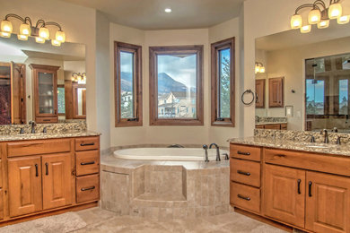 Large elegant master beige tile and ceramic tile ceramic tile bathroom photo in Denver with raised-panel cabinets, medium tone wood cabinets, granite countertops, a one-piece toilet, beige walls and an undermount sink