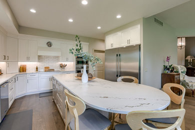 Transitional u-shaped light wood floor eat-in kitchen photo in Other with an undermount sink, shaker cabinets, white cabinets, quartz countertops, white backsplash, subway tile backsplash, stainless steel appliances, an island and white countertops