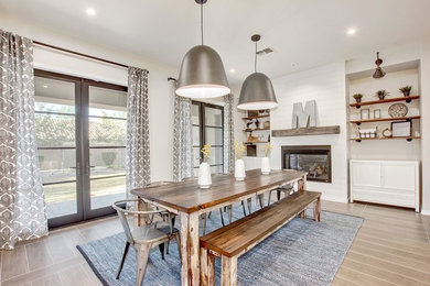 Inspiration for a mid-sized shabby-chic style porcelain tile enclosed dining room remodel in Phoenix with white walls, a standard fireplace and a wood fireplace surround