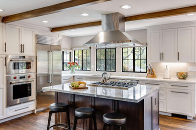 Inspiration for a mediterranean medium tone wood floor, brown floor and exposed beam eat-in kitchen remodel in San Francisco with shaker cabinets, white cabinets, stainless steel appliances, an island, white countertops and granite countertops