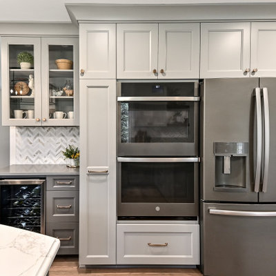 Inspiration for a huge farmhouse l-shaped medium tone wood floor and brown floor eat-in kitchen remodel in Milwaukee with a farmhouse sink, shaker cabinets, gray cabinets, quartz countertops, white backsplash, marble backsplash, stainless steel appliances, an island and gray countertops