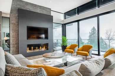 This is an example of a large contemporary open concept living room in Vancouver with white walls, light hardwood floors, a standard fireplace, a stone fireplace surround and a wall-mounted tv.