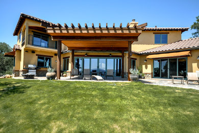Inspiration for a large mediterranean yellow two-story concrete gable roof remodel in Sacramento