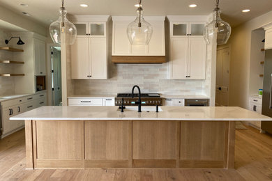 Example of a large transitional u-shaped light wood floor eat-in kitchen design in Portland with a single-bowl sink, shaker cabinets, medium tone wood cabinets, quartz countertops, white backsplash, porcelain backsplash, stainless steel appliances, an island and white countertops