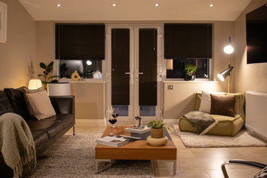 This is an example of a modern formal enclosed living room in Cambridgeshire with beige walls, ceramic flooring, a wall mounted tv and a vaulted ceiling.