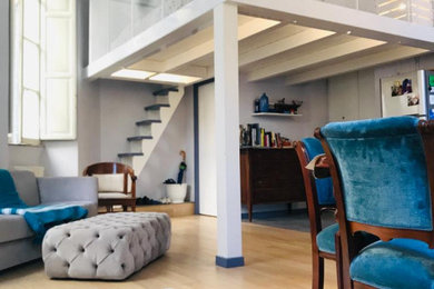 Ejemplo de salón tipo loft mediterráneo de tamaño medio con paredes azules, suelo de madera clara y suelo beige