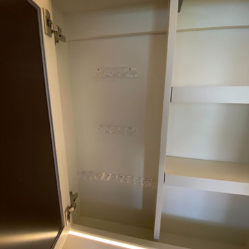 Hidden storage behind the mirror for hanging jewelry and storing hair dryer and