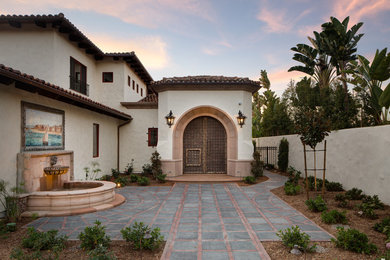 Large mediterranean beige two-story stucco exterior home idea in San Diego with a tile roof